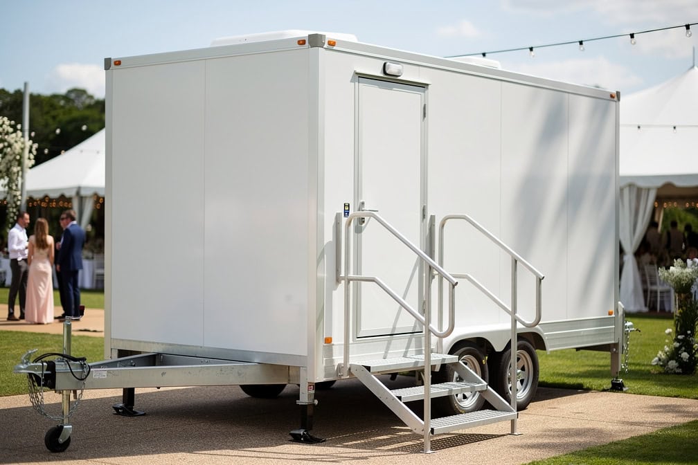 Restroom trailer at an outdoor venue with guests in the background